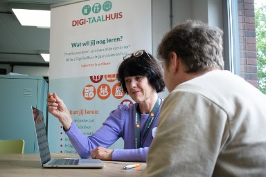 Bibliotheekmedewerker geeft uitleg aan bezoeker op de computer.